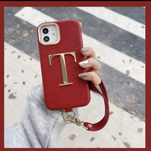 Czerwone etui z paskiem metalową literką Iphone 15